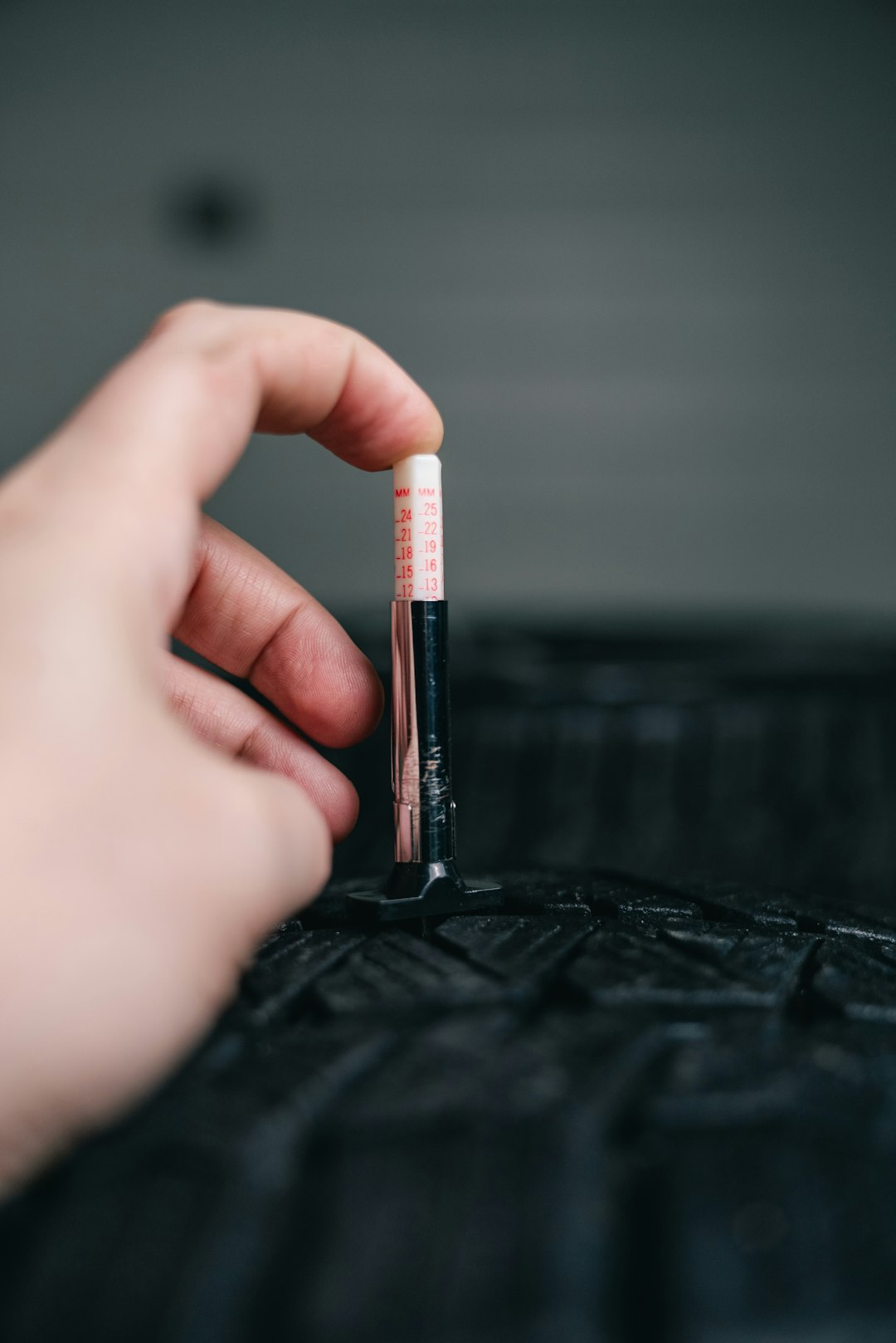 hand-measuring-tire-tread-depth-with-gauge-zrwj7flyrlk